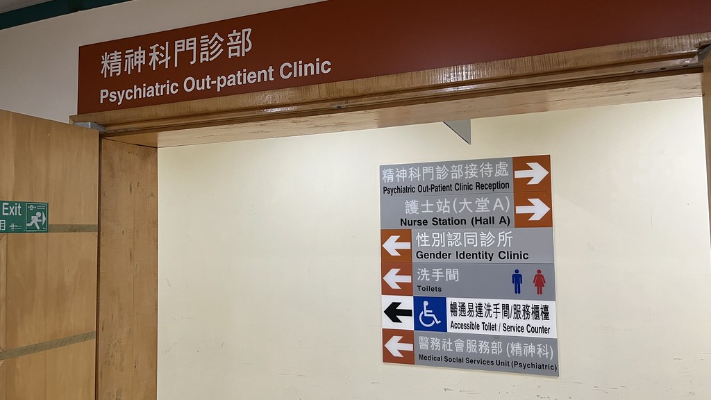 Hospital signs above a doorway: Psychiatric Out-patient Clinic, and a sign pointing to the Gender Identity Clinic, toilets and an accessible toilet.